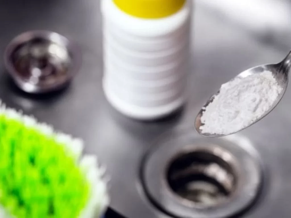 Imagem de uma pia entupida com uma pessoa tentando desentupir.